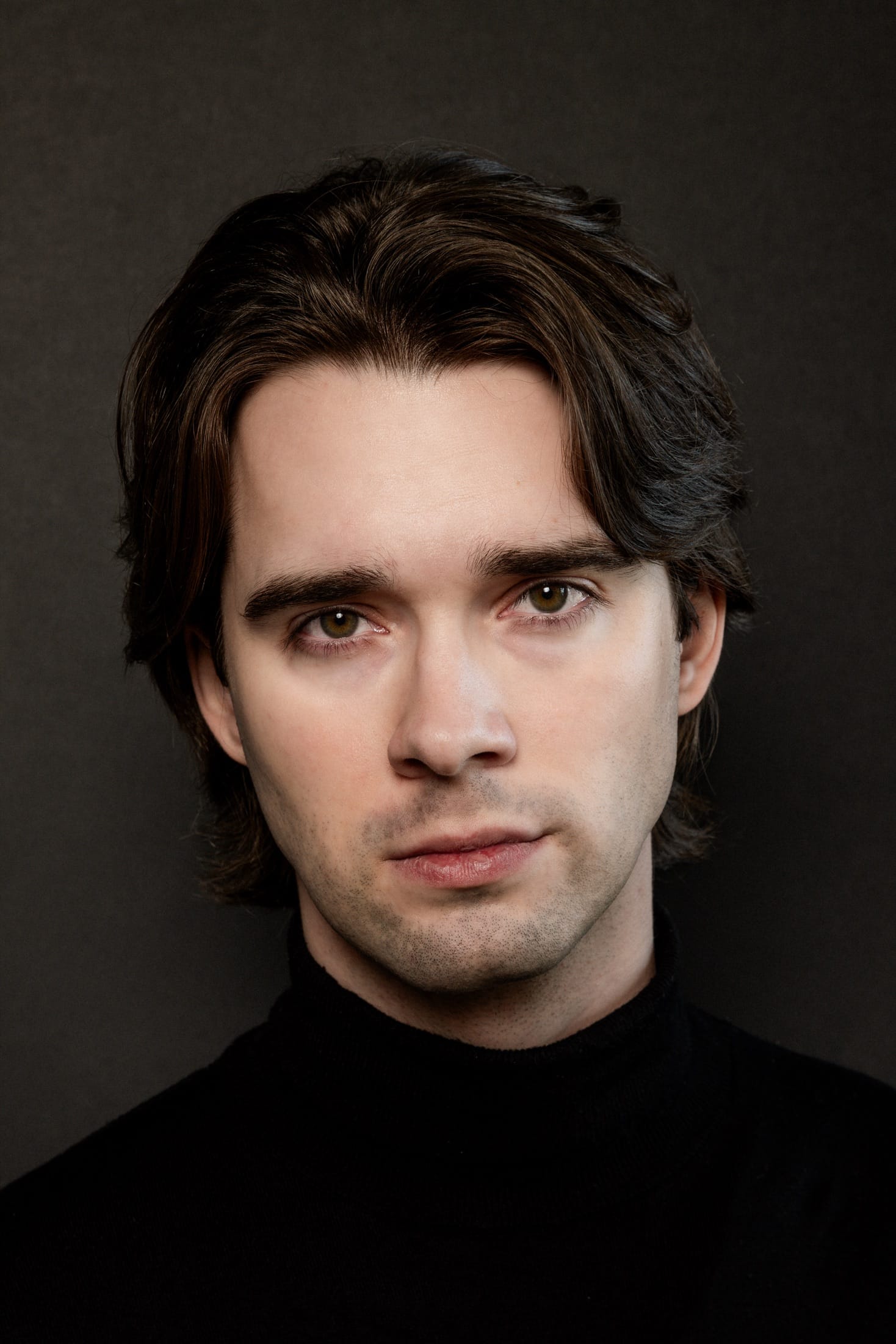 Headshot, black turtleneck, dark background